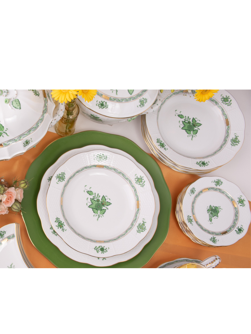 Elegant green and white floral porcelain dinnerware set on orange table with yellow flowers